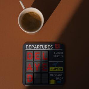 Mock up image with coffee mug of Departures Flight Board 'Delayed' 4-Pack Coasters Set Black